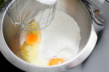 Mixing ingredients. Metal bowl with cracked egg and flour. Pancake batter background. Making pizza...