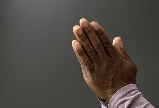 man praying to God with hands together on black background with people stock image stock photo