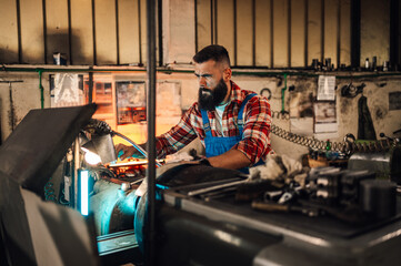 A young factory worker operating a machine, frowned, in a manufacture.