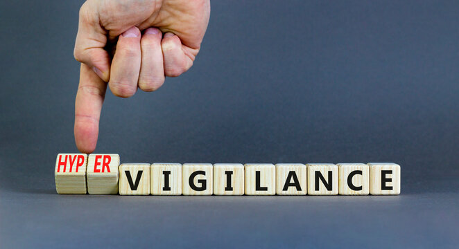 Vigilance or hypervigilance symbol. Concept words Vigilance Hypervigilance on wooden blocks. Beautiful grey background. Psychologist hand. Psychology vigilance hypervigilance concept. Copy space.