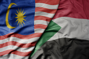 big waving realistic national colorful flag of malaysia and national flag of sudan .