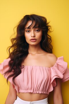 Elegant Mexican woman in pink blouse against a vibrant yellow backdrop.