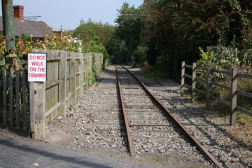 Fototapeta na wymiar Tramway line with raised iron tramway tracks, gravel and fence enclosure