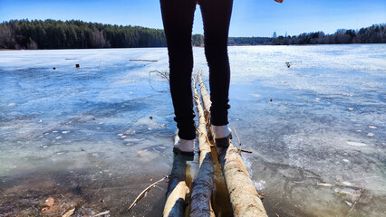 An old wooden pier on the shore of a lake with ice in early spring on a sunny day. Freezing lake in...