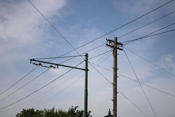 Overhead tramway cables and a vintage telegraph pole, cloudy sky in background