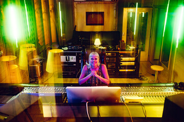 Portrait of a young female music producer in a music studio.