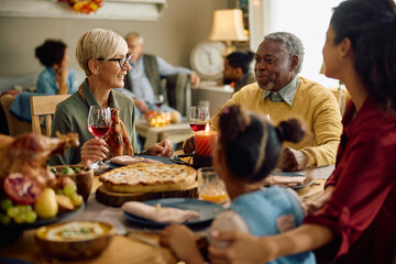 Happy senior couple communicating at dining table while celebrating Thanksgiving with their family.