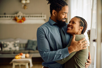 Happy black couple in love embracing at home.