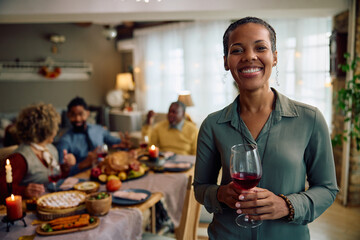 Happy black woman with her family on Thanksgiving and looking at camera.