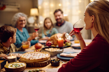 Happy woman drinks wine during family dinner on Thanksgiving.
