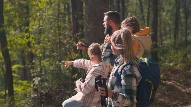Smiling family of four enjoying hiking in trough forest.