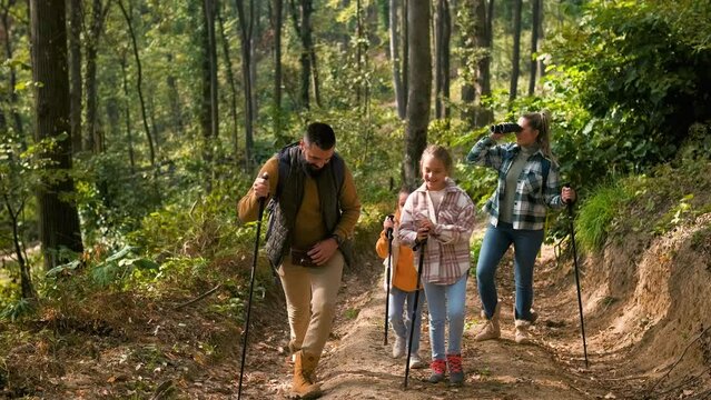 Smiling family of four enjoying hiking in trough forest.