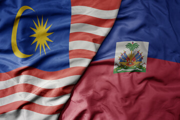 big waving realistic national colorful flag of malaysia and national flag of haiti .