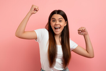 Overjoyed teen girl celebrating success, shaking fists and looking at camera