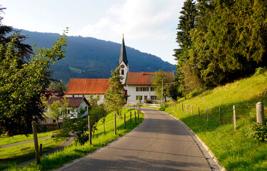 a road leading to a beautiful old church in the Bavarian Alps on a sunny September day in the...