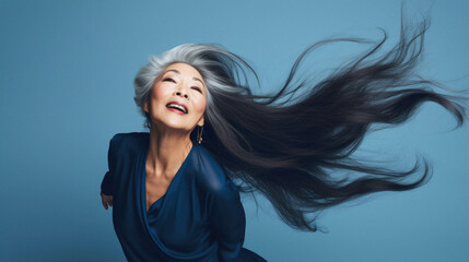 Asian older senior mature woman posing in studio with flying hair, motion portrait.