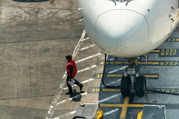High angle close up view of nose of an aircraft parked on yellow airport gate markings on the...