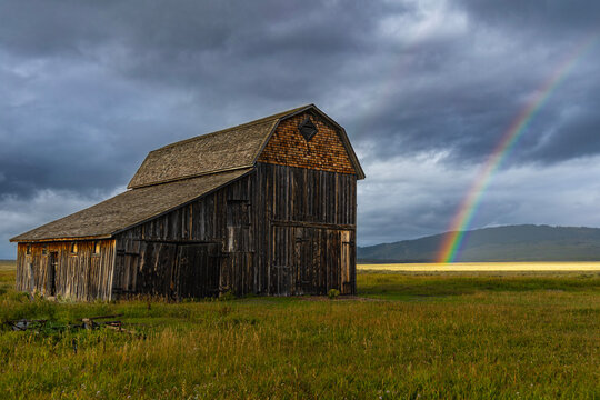 old barn in the field with rainbow
