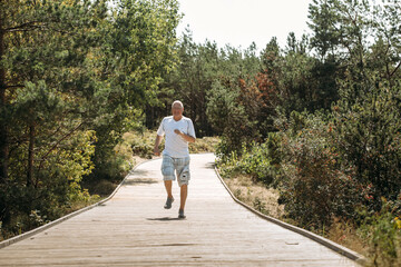 A joyful elderly man runs along a path in a park