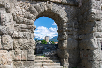 View through one of the arches of the ancient Roman Theatre in Aosta, Italy built in reign of Augustus, with snowcapped mountains of Italian alps in background