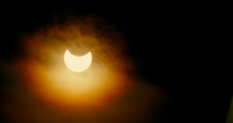 Sun’s crescent burns through thin layers of cloud cover during the partial solar eclipse of 2014.