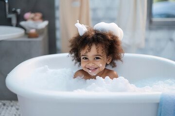 Soap foam, bath time, little african American child girl taking bubble bath in beautiful bathroom, Kids hygiene Shampoo, hair treatment and soap for children, Kid bathing in large tub , foam in hair.