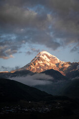 An Early morning view of a snowcapped Kazbegi Mountain with clouds surrounding it