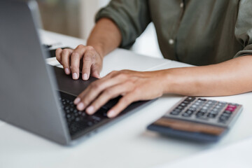 Businesswoman using laptop with technology to typing and working about calculation tax in office..