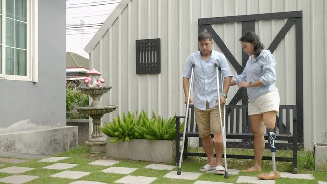 woman wearing prosthetic legs helps her husband injured in an accident using crutches.equality concept, disability, life difficulties
