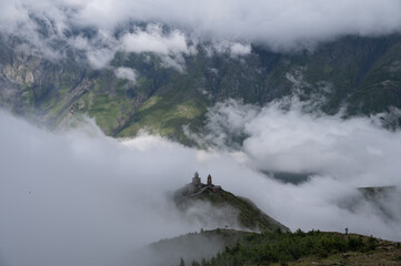 A view of the iconic Trinity Church in Stepantsminda surrounded by low clouds