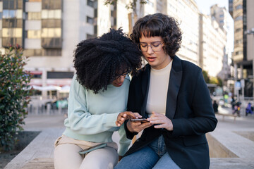 Two friends looking at smartphone in the street