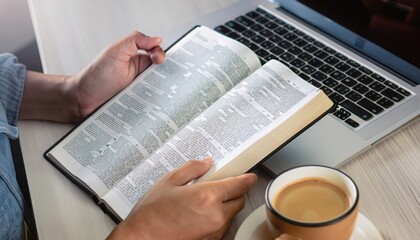 to understand the Bible in order to pray to God and to ask God to protect himself and his family. Online bible, Hands holding a cup of coffee and a bible placed on a laptop were opened for learning