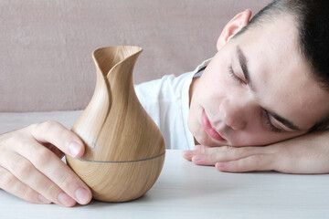 Diffuser. Nearby lies a wooden bamboo,
  an electric jug in the hand of a young man who has closed...