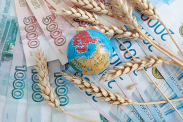Globe and wheat ears on Russian rubles, in denominations of 2000 and 5000. Concept of yield on the planet, export and import of grain. Crisis situation, wartime famine, grain deal.