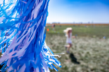 Selective focus on a pom-pom streamer with defocused child running in the background 