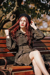 Girl in coat sits on a bench in an autumn park
