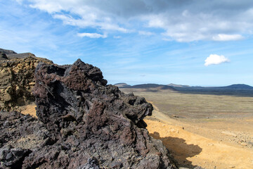 Fototapeta na wymiar Big chunk of lava rock with in background panoramic view over volcanic landscape on Reykjanes Peninsula, Iceland, near sites of 2021 and 2022 eruptions near mountain Fagradalsfjall volcano area