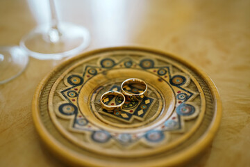 Two gold wedding rings on a beautiful carved plate. Wedding ceremony.