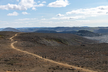 Panoramic view over lava field with hikers on path near mountain Fagradalsfjall with fissure vent of 2021 in Geldingadalir volcano area to the south of Fagradalsfjall mountain, Iceland