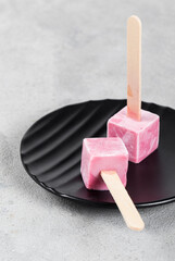Raspberry ice cream mini cubes on a stick. On a plate.  Close up. Copy space
