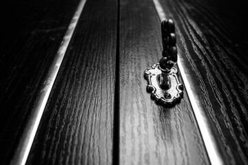Key is in the keyhole of an antique cabinet door. Closed mysterious door with an old key. - obrazy, fototapety, plakaty