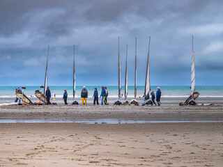 Activities on the beach at low tide. Men and women ready to go sand yachting. Coastline of Upper Normandy, France
