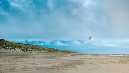 Walking on the beach at low tide in winter. A Kitesurfing wing in the sky. Coastline of Upper Normandy, France