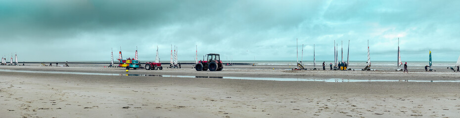 Panorama of a beach at low tide. Sand yachting activities and a tractor for transporting equipment. Coastline of Upper Normandy, France