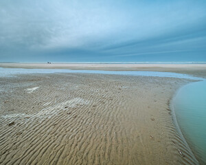 View of the beach at low tide, a cloudy winter sky and rippled sand. Coastline of Upper Normandy, France