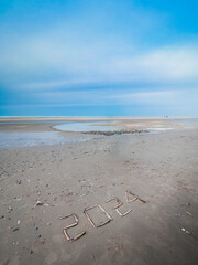 New year 2024 written with shells on a beach at low tide.
