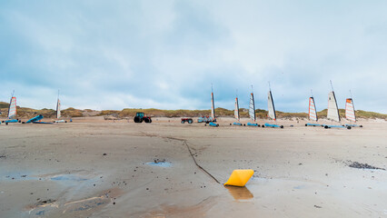 Storage of sand yachts on a beach at low tide. In winter between coast and sand a yellow buoy in the foreground. Coastline of Upper Normandy, France