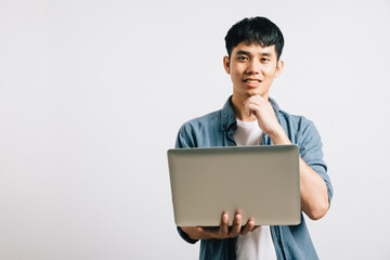 A closeup portrait of a thoughtful Asian man, hand on chin, holding a laptop, pondering questions and looking away. Studio shot isolated on white, where success is born from deep thinking.