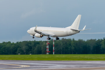 An unmarked white passenger jet comes in for a landing at an airport. Jet commercial aviation