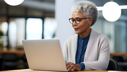 Dedicated african american woman, 60, working on her computer in an office